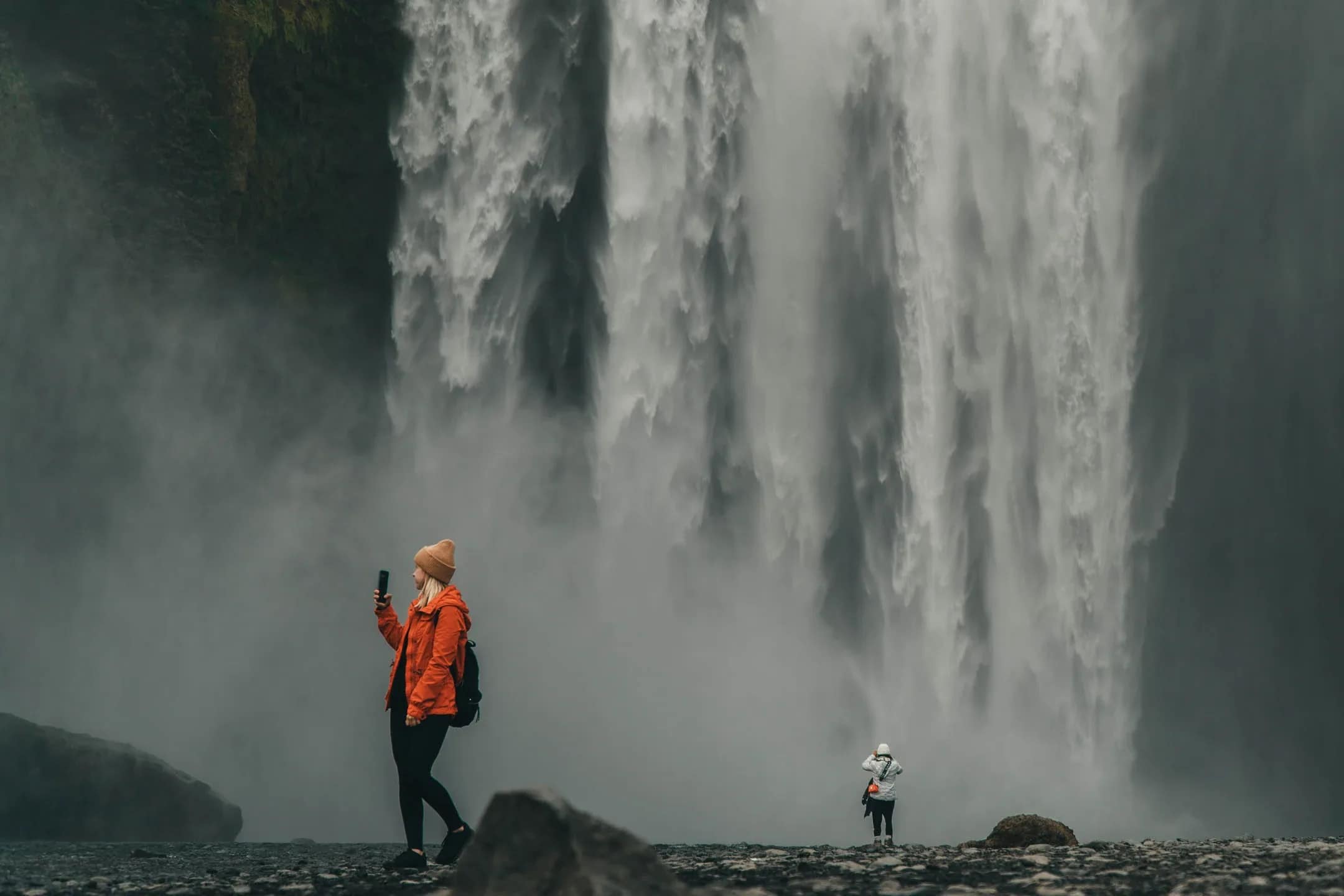 Person photographing a massive waterfall in Iceland, representing free things to do in Iceland for nature lovers