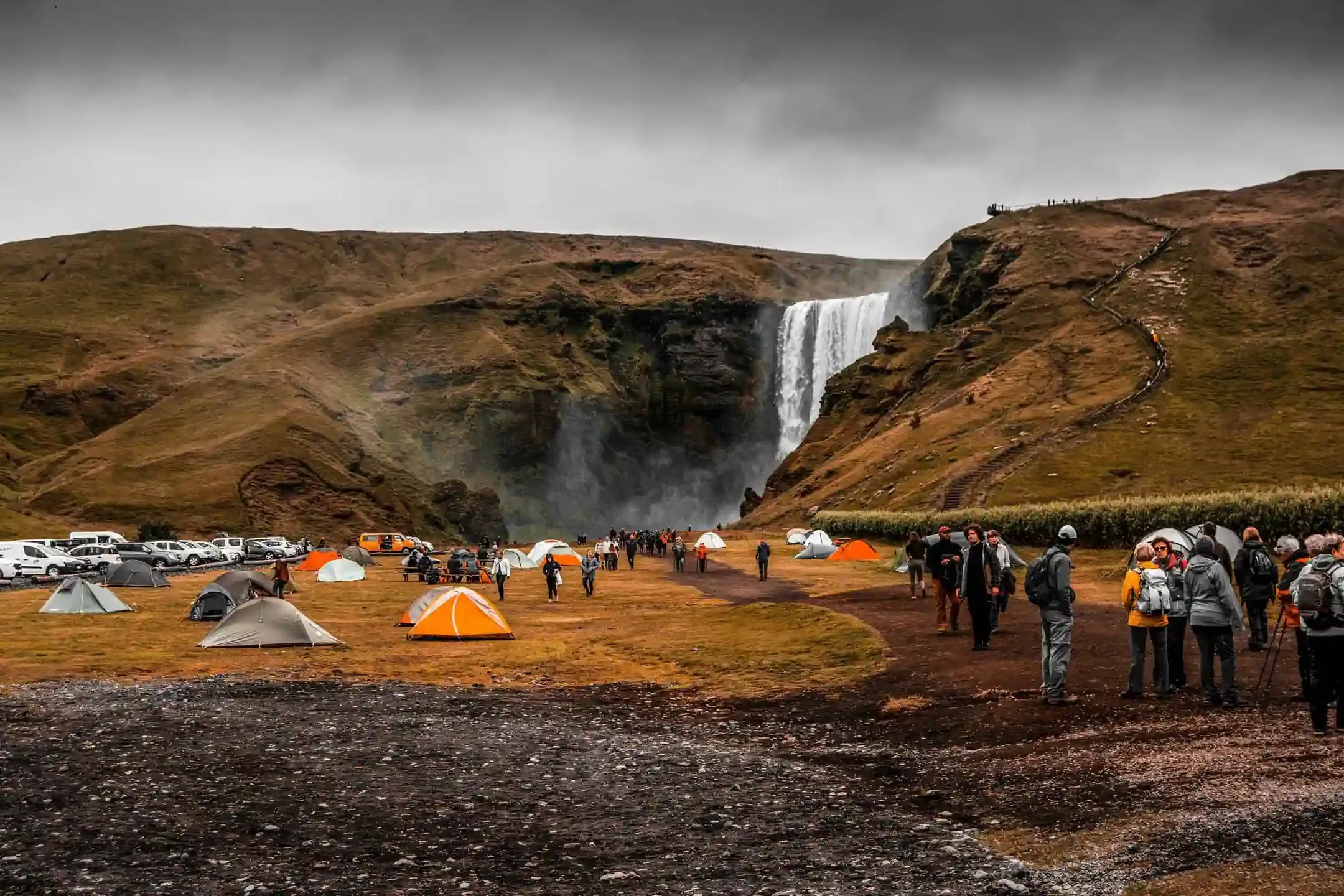 Skogafoss campsite in Iceland with tents and travelers, showing legal alternatives to sleep in a campervan anywhere in Iceland