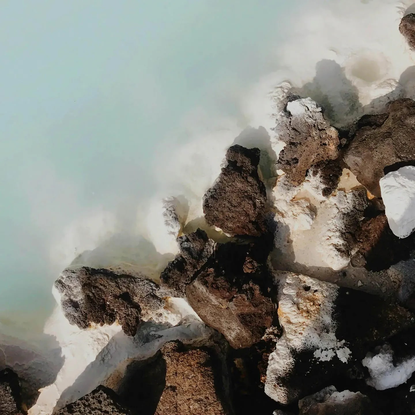 Close-up of geothermal water and lava rocks at a natural hot spring in Iceland.
