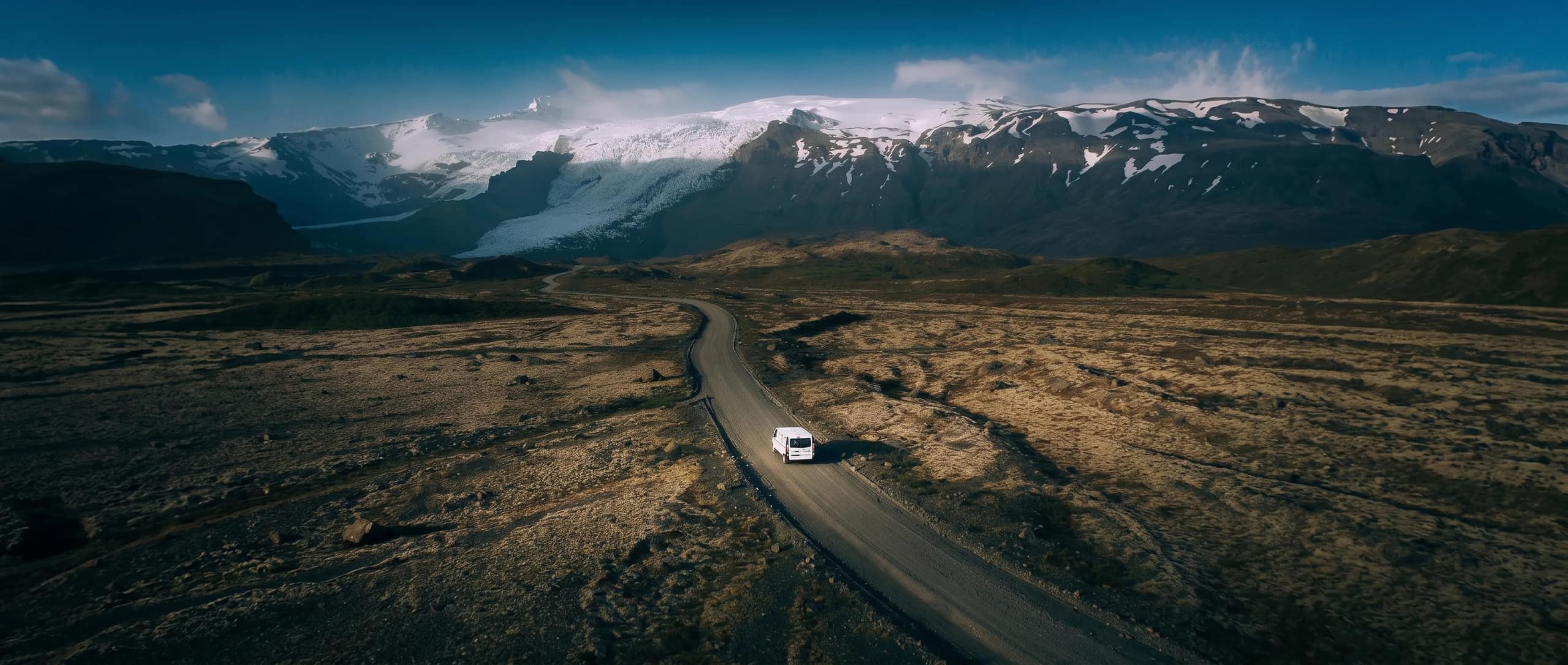 Foxie camper on a gravel road toward an Icelandic glacier