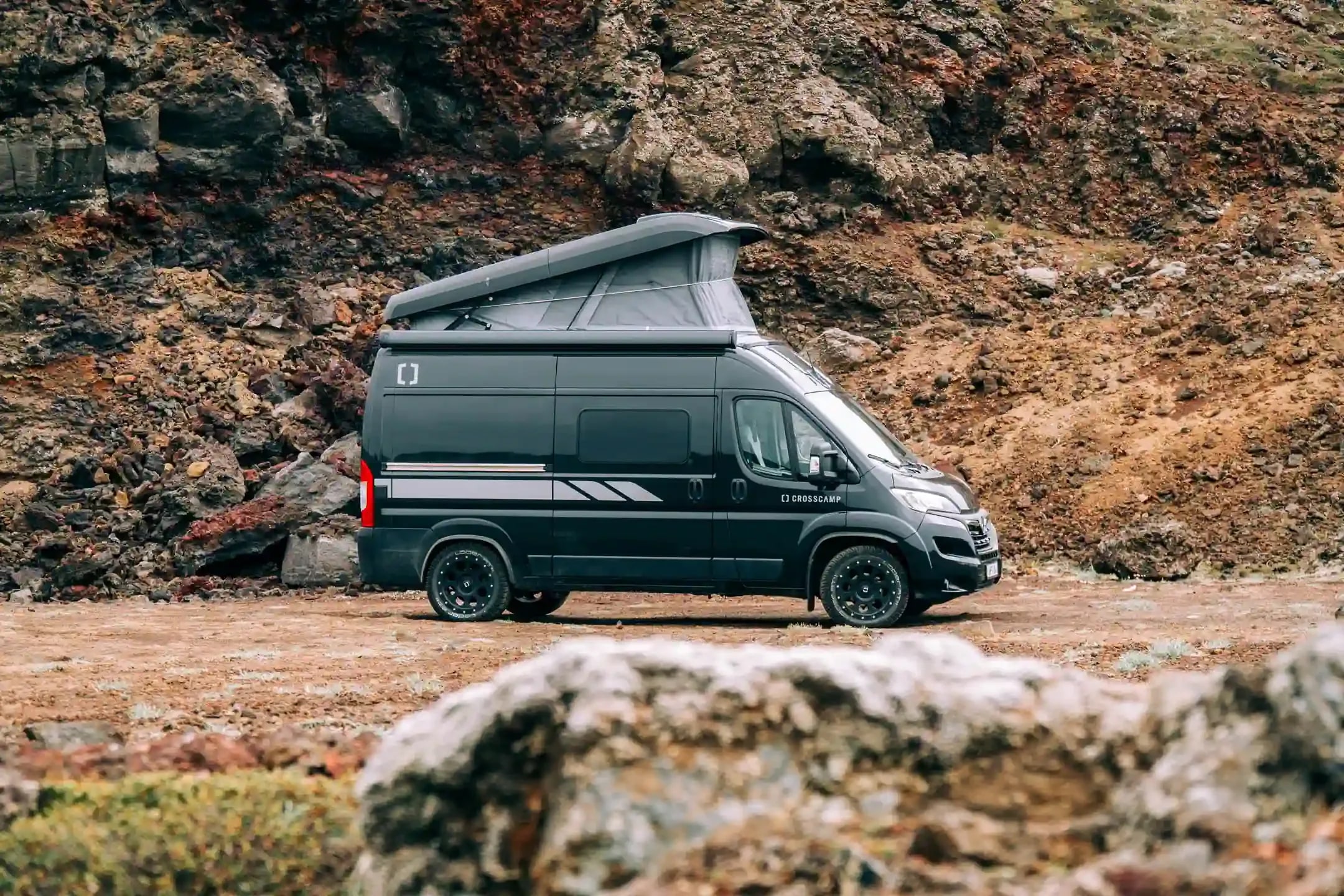 Campervan camping in Iceland with a modern black campervan parked in a volcanic landscape.