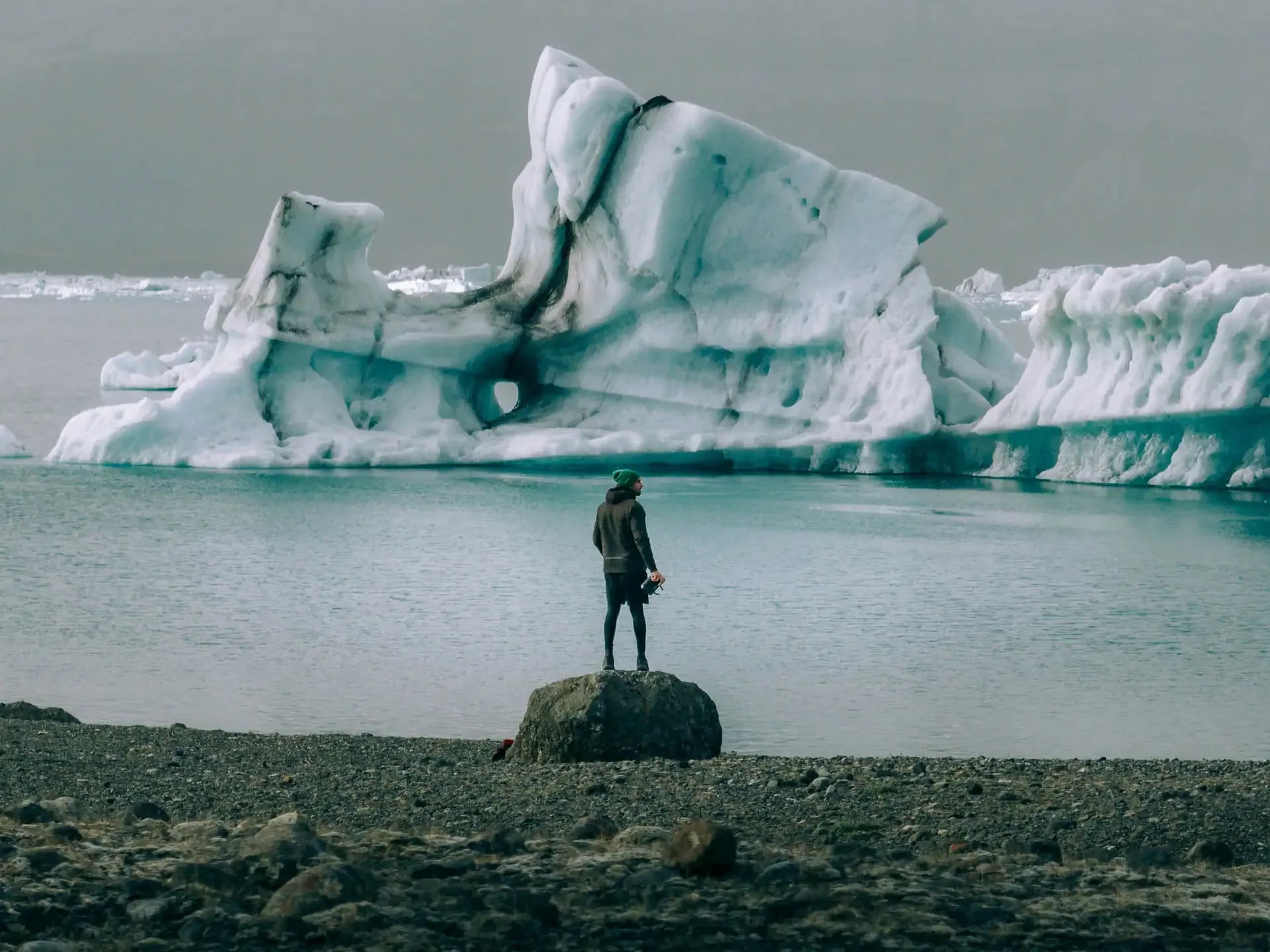 Traveler standing near floating icebergs at a glacier lagoon in Iceland during a campervan road trip adventure